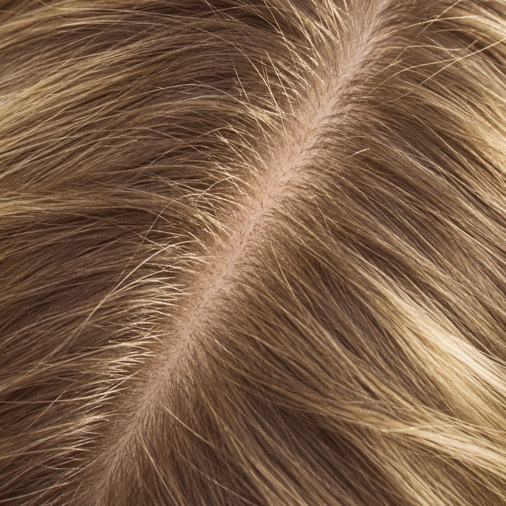 Close-up of a centre part in light brown hair with fine new hairs along it